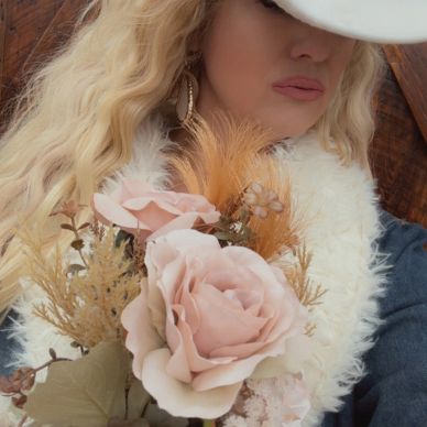 Woman in white cowboy hat holding a bouquet of flowers.