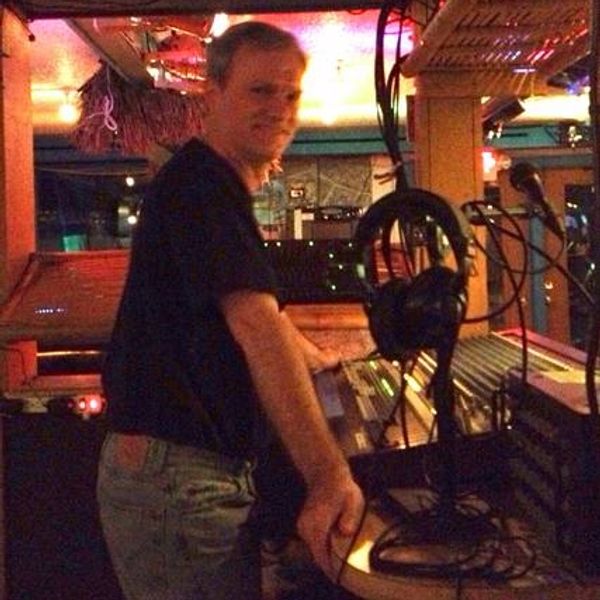 A man operating audio equipment in a dimly lit studio or control room.
