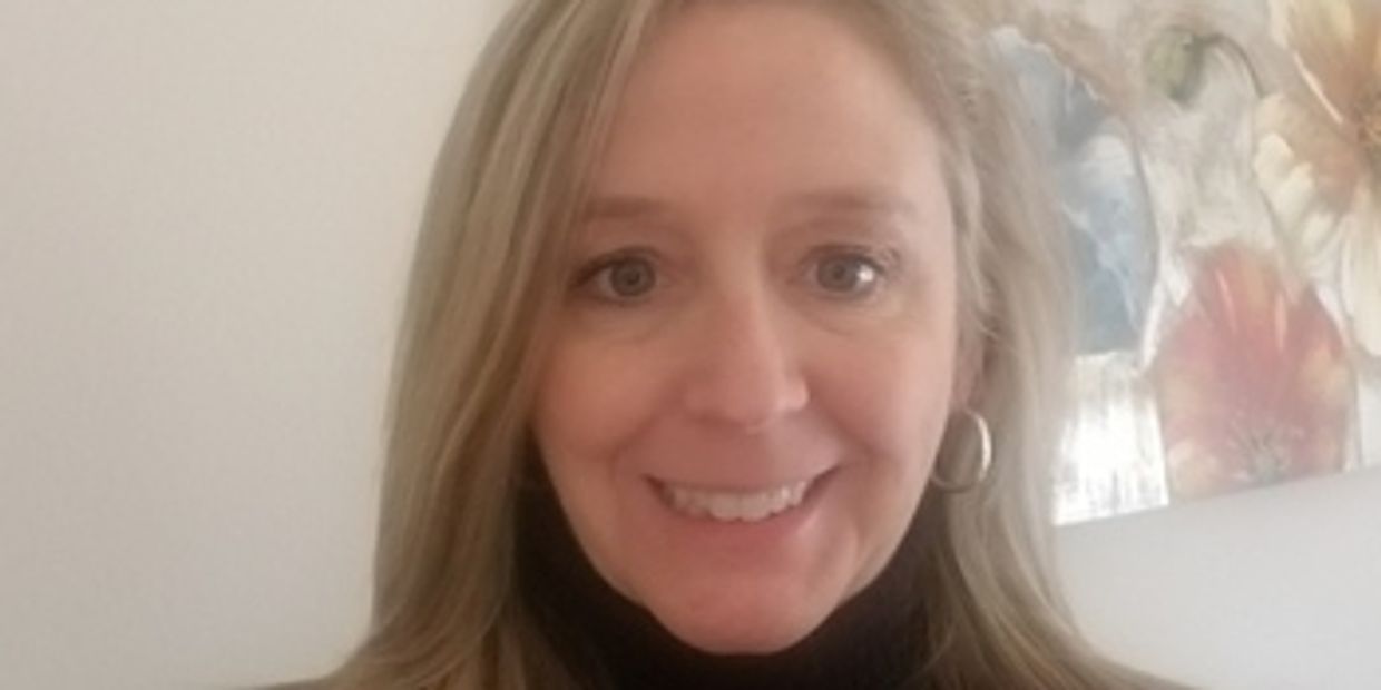 A smiling woman with blonde hair and hoop earrings.