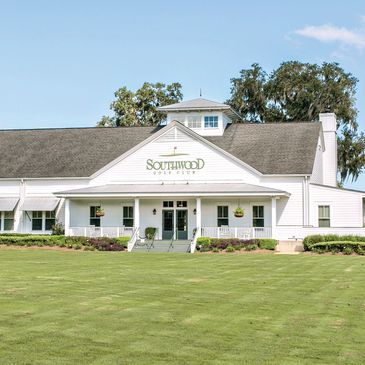 White clubhouse building of SouthWood Golf Club with a green lawn.
