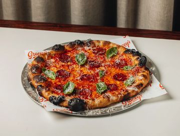 Pepperoni pizza with fresh basil and charred crust.