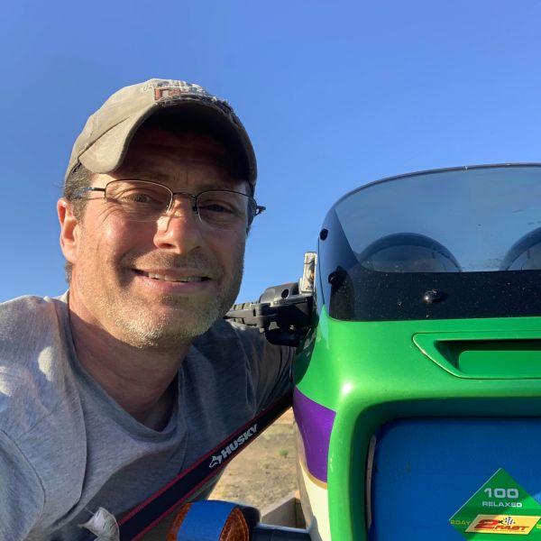 Man smiling next to a green vehicle.