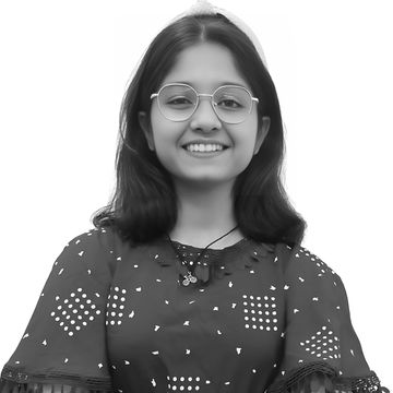 Smiling woman in glasses and red top with arms crossed.