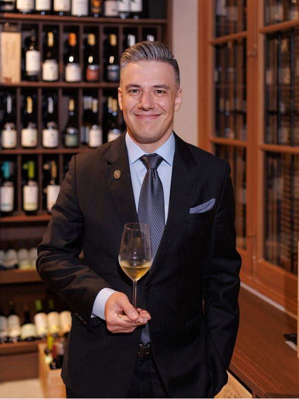 Homem elegante com taça de vinho branco.