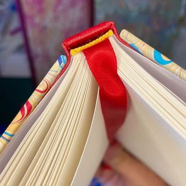 opened book top edge detail showing red spine and red ribbon marker