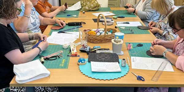 Group crafting session with sewing and embroidery materials.