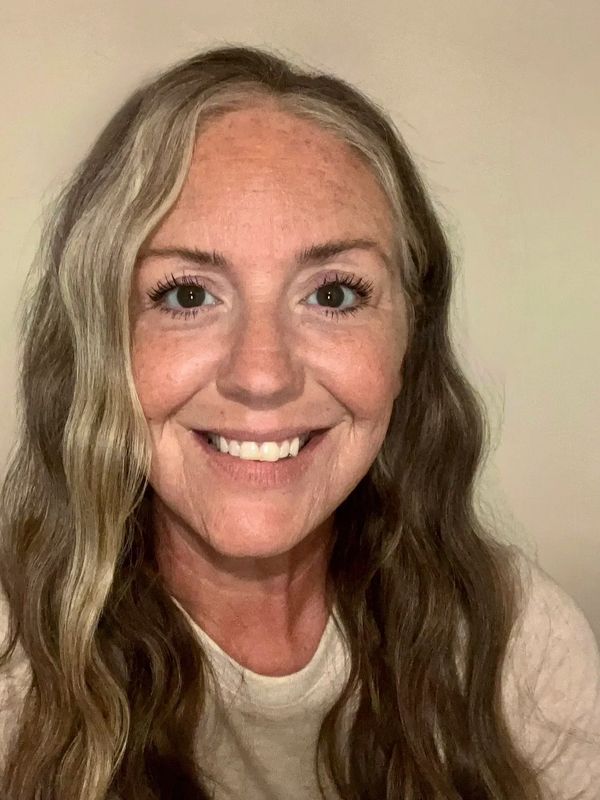 Smiling woman with long wavy hair and freckles.