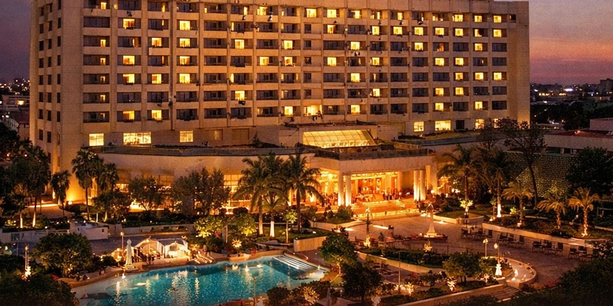Luxury hotel illuminated at dusk with pool and palm trees.