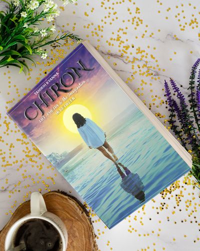 Book titled 'CHIRON' surrounded by flowers and coffee.
