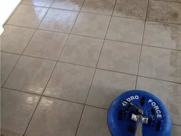 A floor cleaning machine is cleaning dirty tiles, revealing a shiny surface.