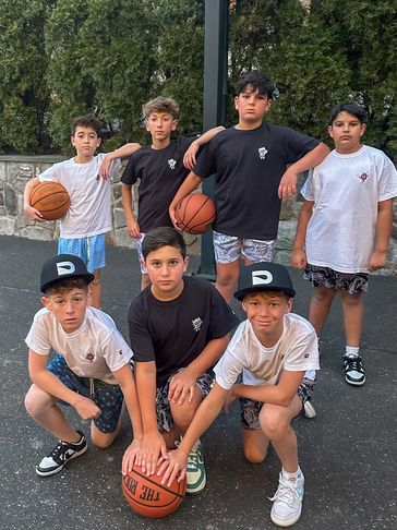Group of young boys posing with basketballs outdoors.
