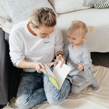 A mother reading a book to her toddler, sharing a cozy and loving moment