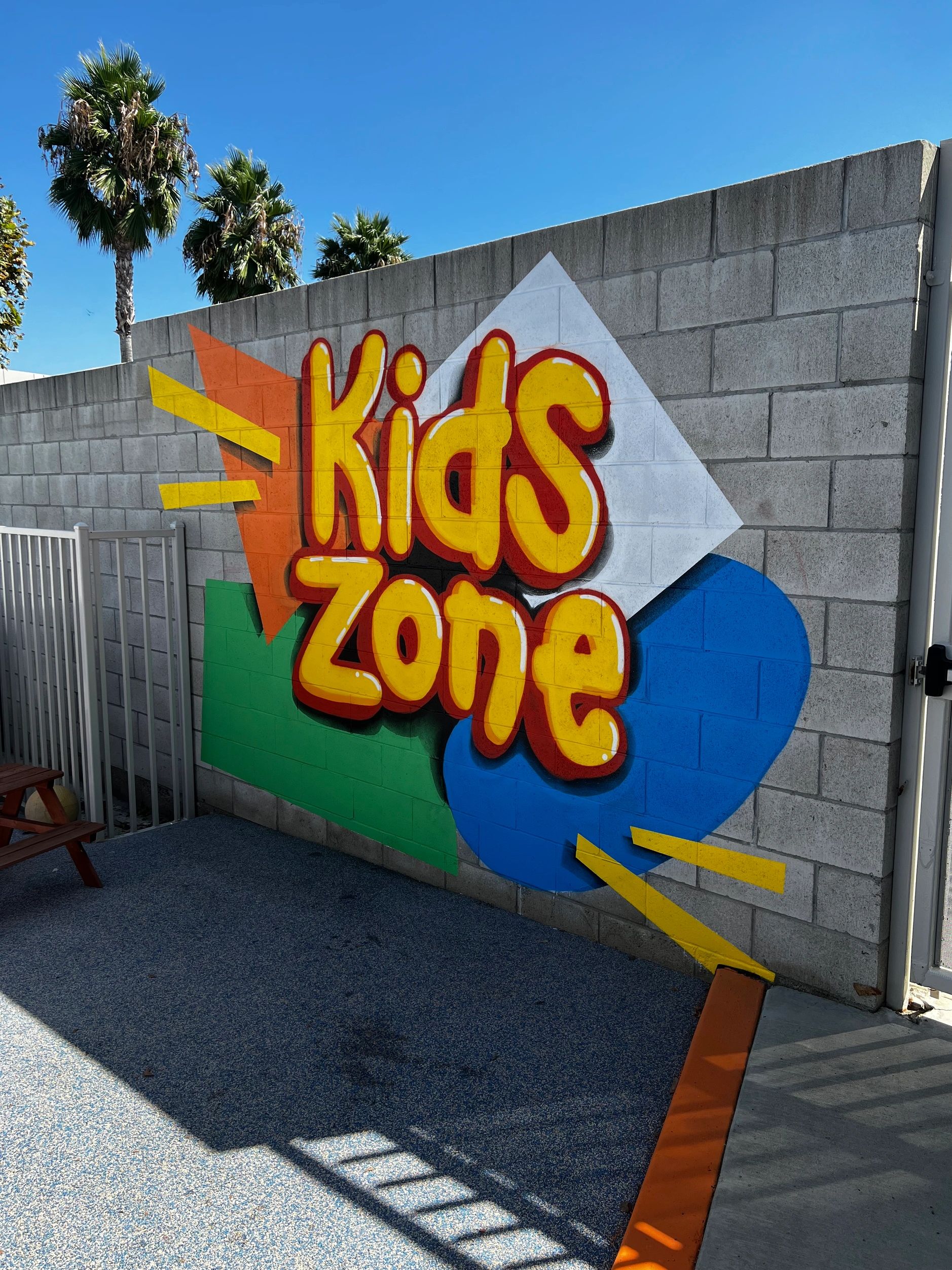 Colorful Kids Zone graffiti on a wall with palm trees.