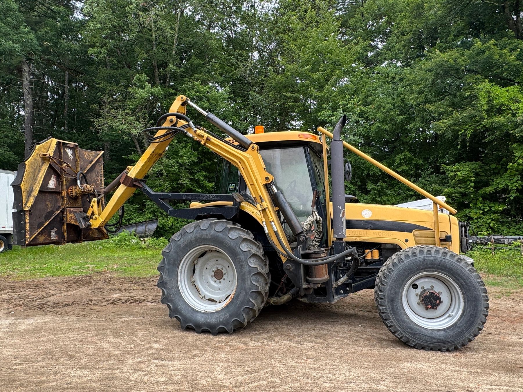 Yellow tractor with large tires and a mechanical arm attachment.