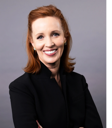 Portrait of a smiling woman with red hair in a black outfit.