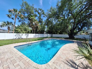 Outdoor swimming pool with clear blue water and greenery.