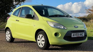 Bright green Ford compact car parked outdoors under a clear sky.