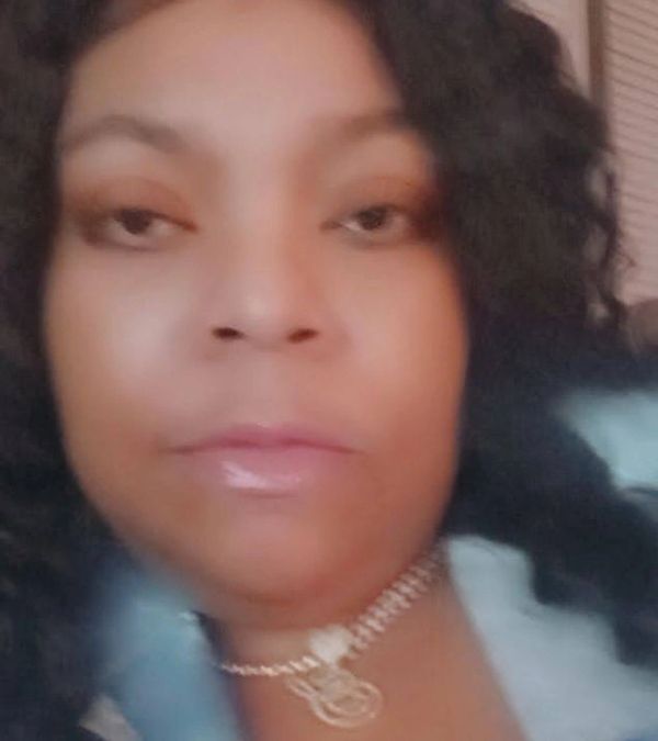 Close-up of a woman with curly hair and a necklace.