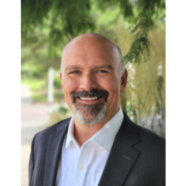 Smiling bald man in suit outdoors.