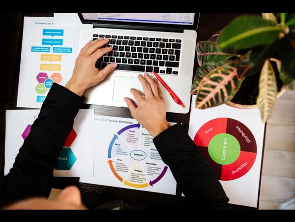 Persona trabajando en marketing con gráficos y computadora.