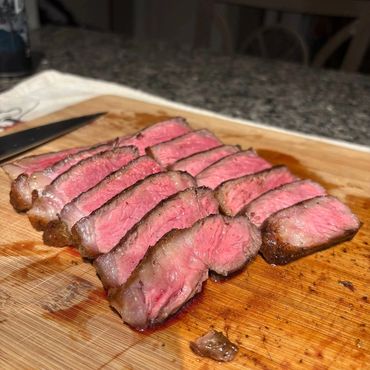 Sliced medium-rare steak on a wooden cutting board.