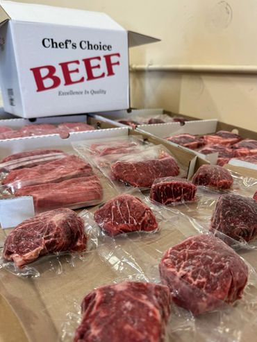 Vacuum-sealed cuts of beef arranged on cardboard with a box labeled Chef's Choice Beef.