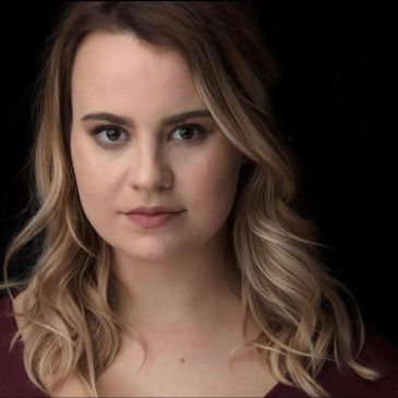 Portrait of a woman with blonde hair against a black background.