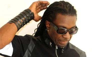 Man with sunglasses and leather wristband adjusting hair.