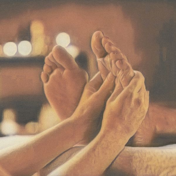 Hands massaging feet in a warm, cozy setting.