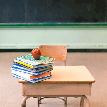 School desk with books and an apple on top. 