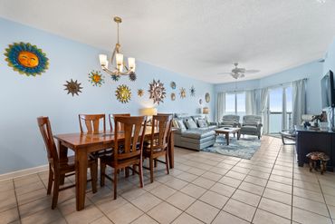 Bright living and dining area with sun-themed wall decor and ocean view.