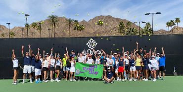 Group of tennis players tossing balls at Nike Tennis Camp in front of mountains.