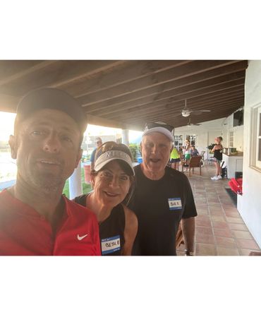 Three people with name tags posing for a selfie at a sunny outdoor gathering.