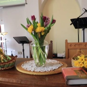 Floral arrangement and a Bible on a table in a church.