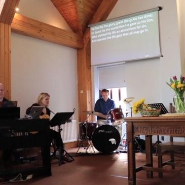 Band playing music in a church with lyrics projected.