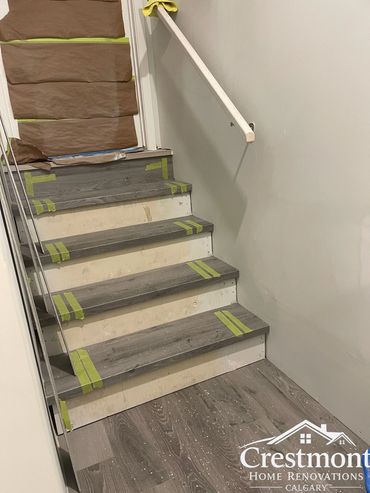 New wood flooring being installed on stairs with protective tape and coverings.