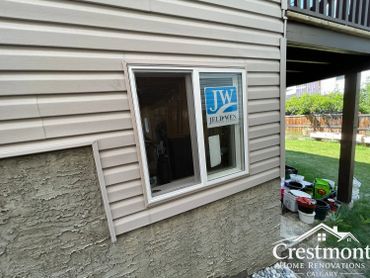 Newly installed window on a house exterior with siding and stucco.