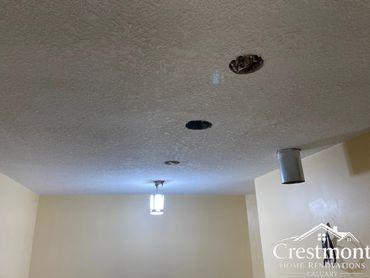 Ceiling with multiple holes and a hanging light fixture.
