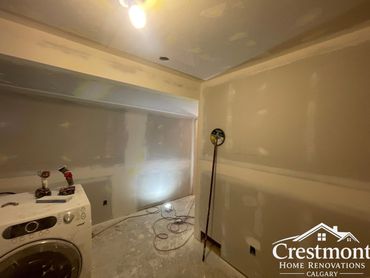 Laundry room under renovation with drywall work in progress.