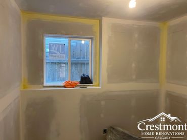 A room under renovation with drywall installation and a small window.