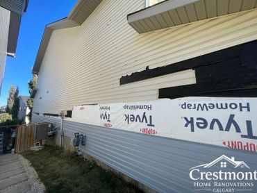 House siding partially removed for renovation under clear blue sky.