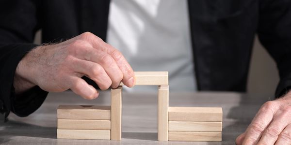 Male hand building a bridge with wooden blocks; concept of association.
