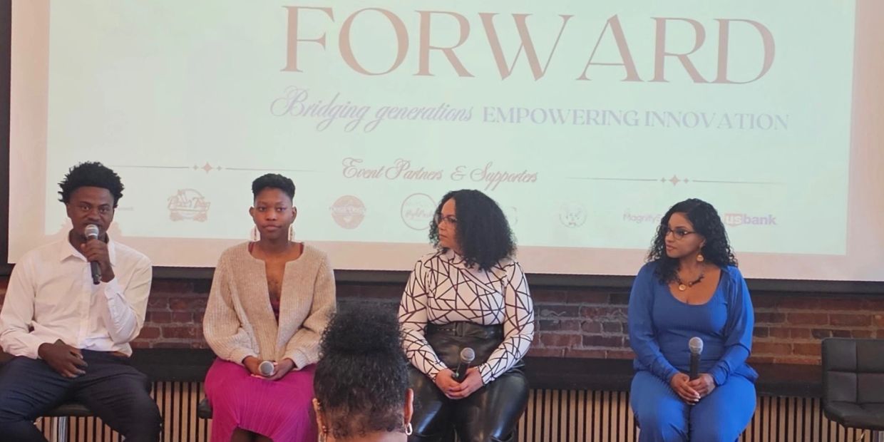 Four panelists holding microphones at a discussion event with a 'FORWARD' banner behind them.