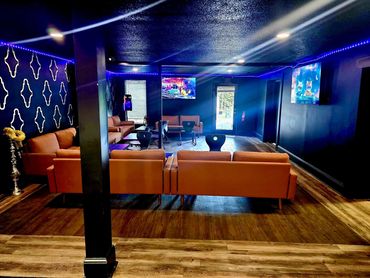 Lounge with orange sofas, black walls, and blue LED lighting.