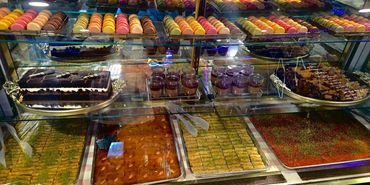 Colorful macarons and various desserts displayed in a glass case at a bakery.