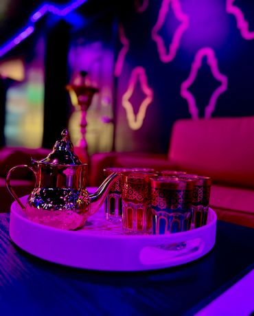 Traditional tea set with ornate glasses in a vibrant, colorful lounge setting.