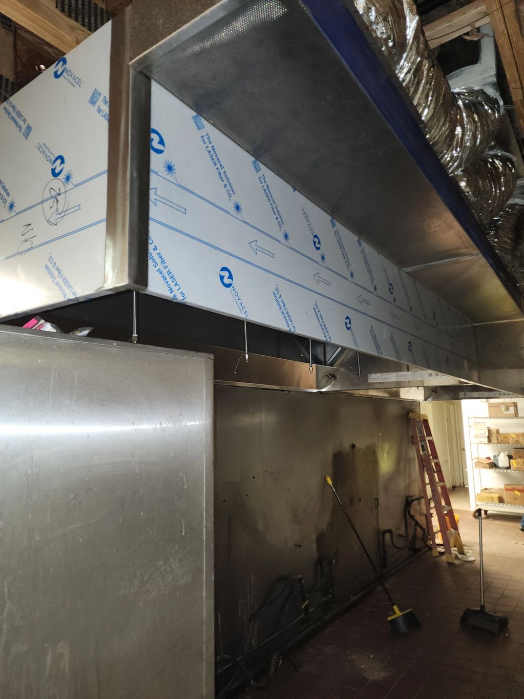 Commercial kitchen exhaust hood and cleaning tools in a restaurant kitchen.