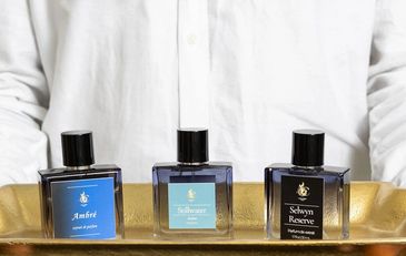 Man holding tray of colognes on gold tray. Highlights walk in perfume making experience