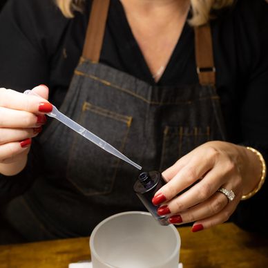 Person using a dropper to add liquid into a container.