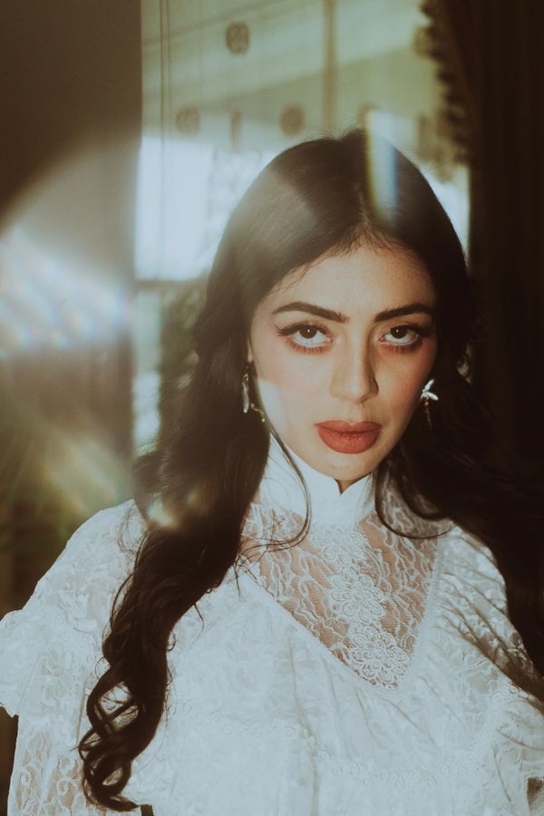 Woman in white lace dress with dramatic makeup and soft lighting.